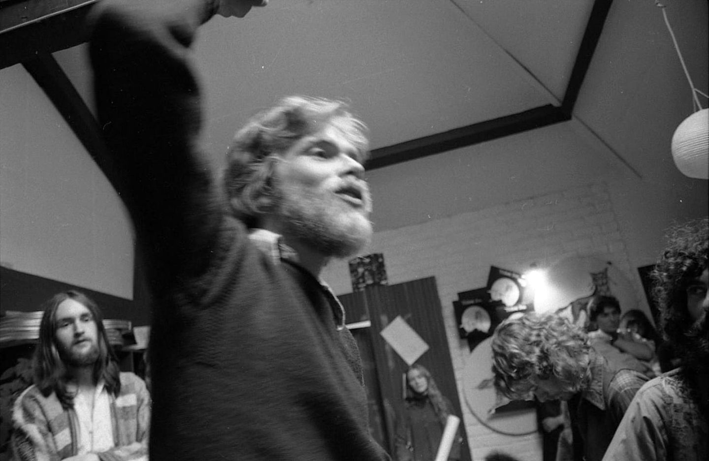 A young, bearded Richard Branson in the studio with his arm raised