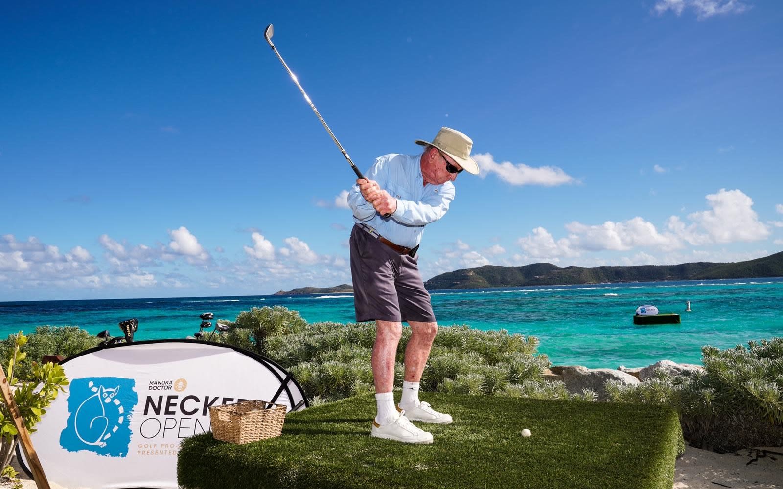 Richard Branson playing golf with sea and mountains in the background