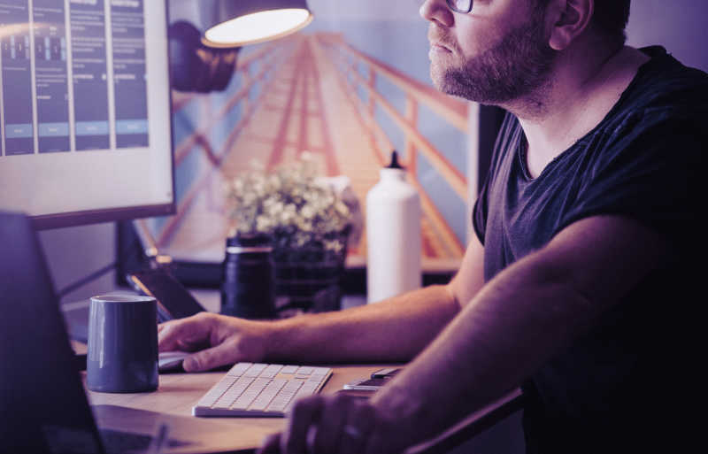 Illustration of man in front of a computer surrounded by water bottle, mug and table lamp