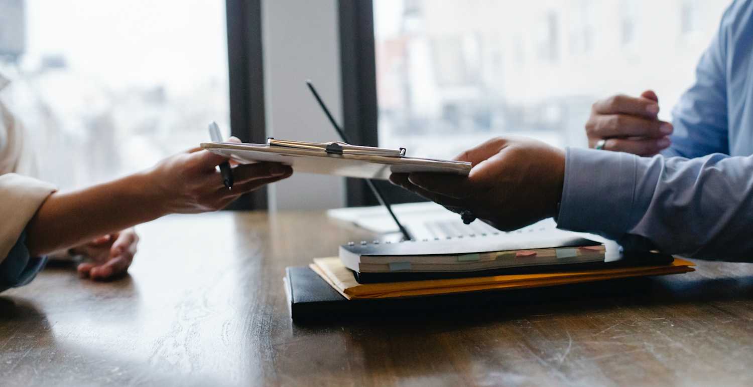 Photo of two people exchanging a clipboard at the workplace