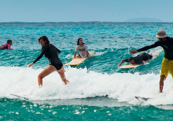 Cours de surf où l'on voit Yohann, le moniteur, donner des conseils aux élèves pour s'améliorer.