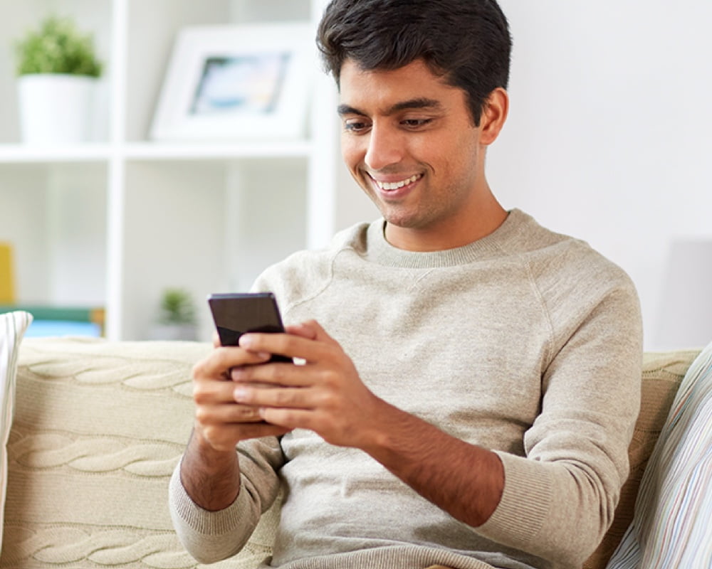Man sitting in his home looking at his mobile device