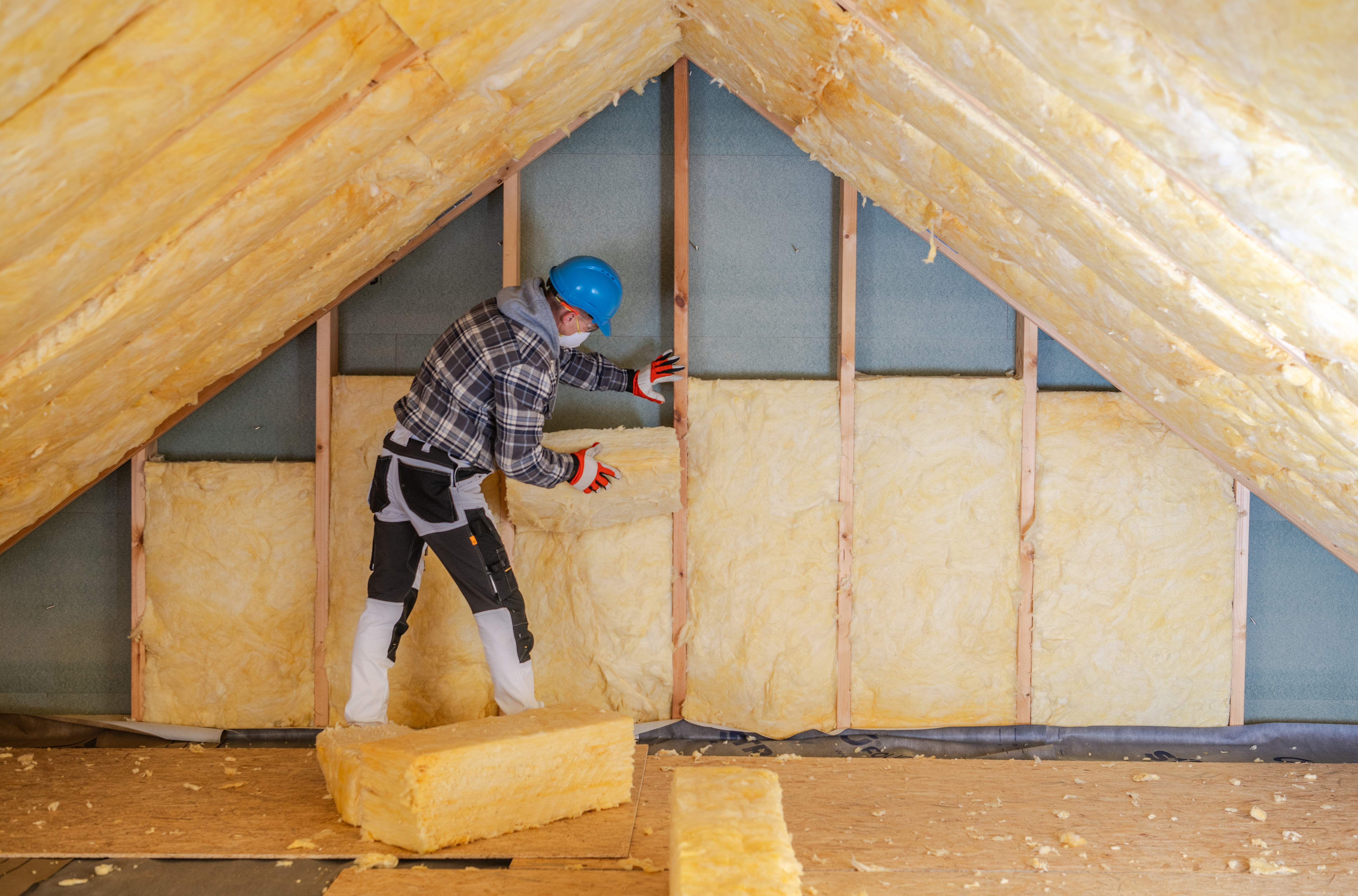 A worker installing loft insulation 