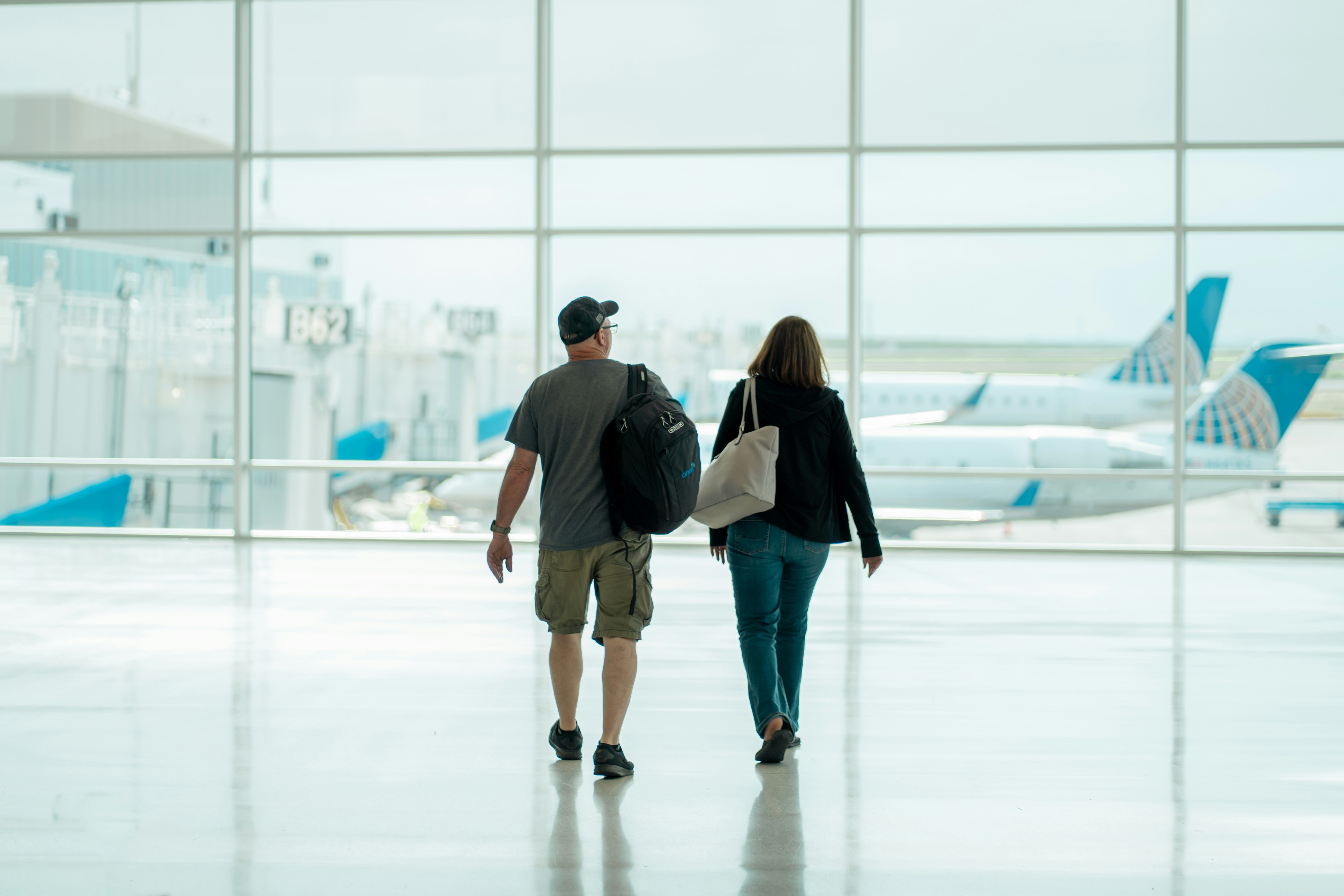 Couple (man and woman) seen from behind with luggage in airport