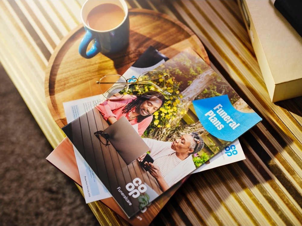Funeral plan brochure on a table with a cup of tea.