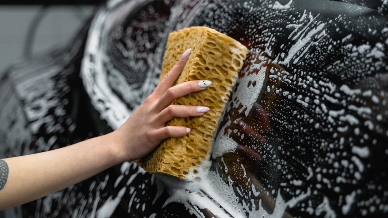 Person washing car with sponge and soap