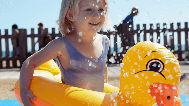 Girl with an inflatable duck playing in swimming pool.