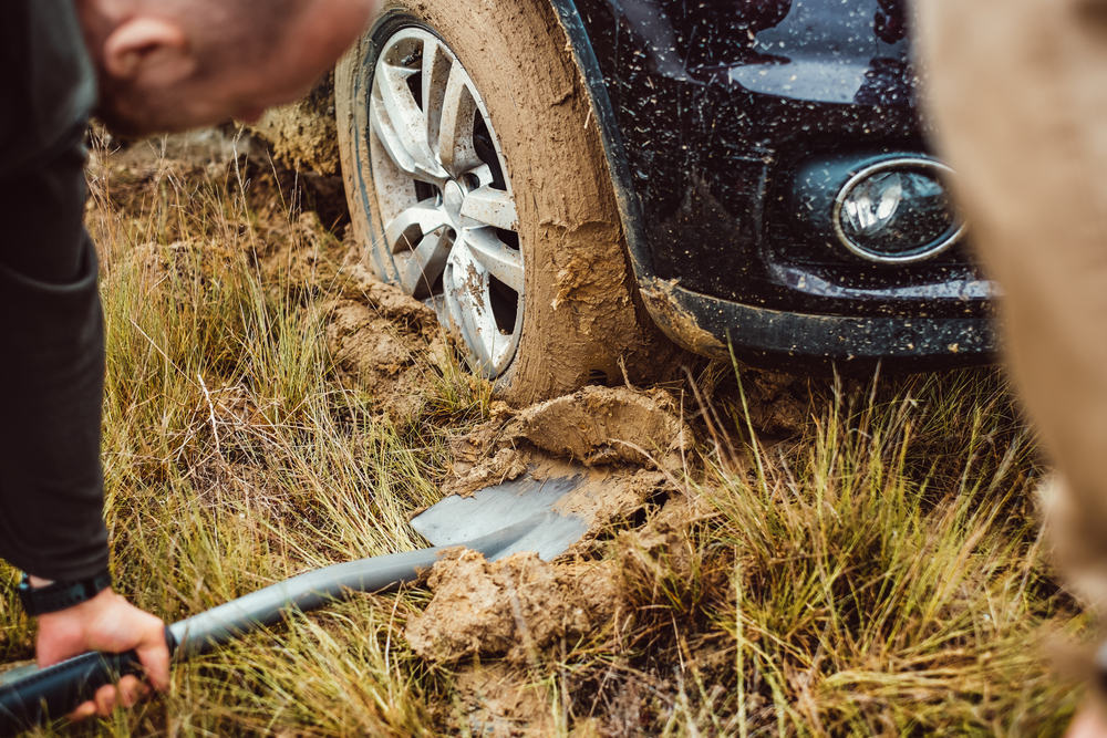 Person using shovel to remove mud from under a tyre
