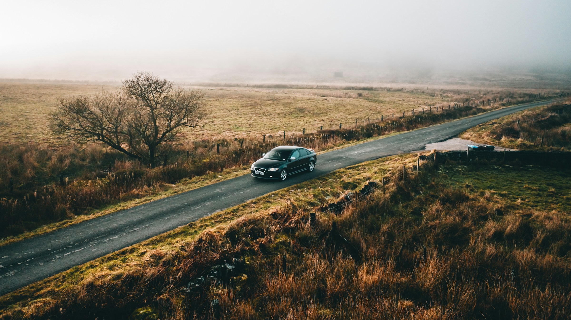 Car driving through fields on road