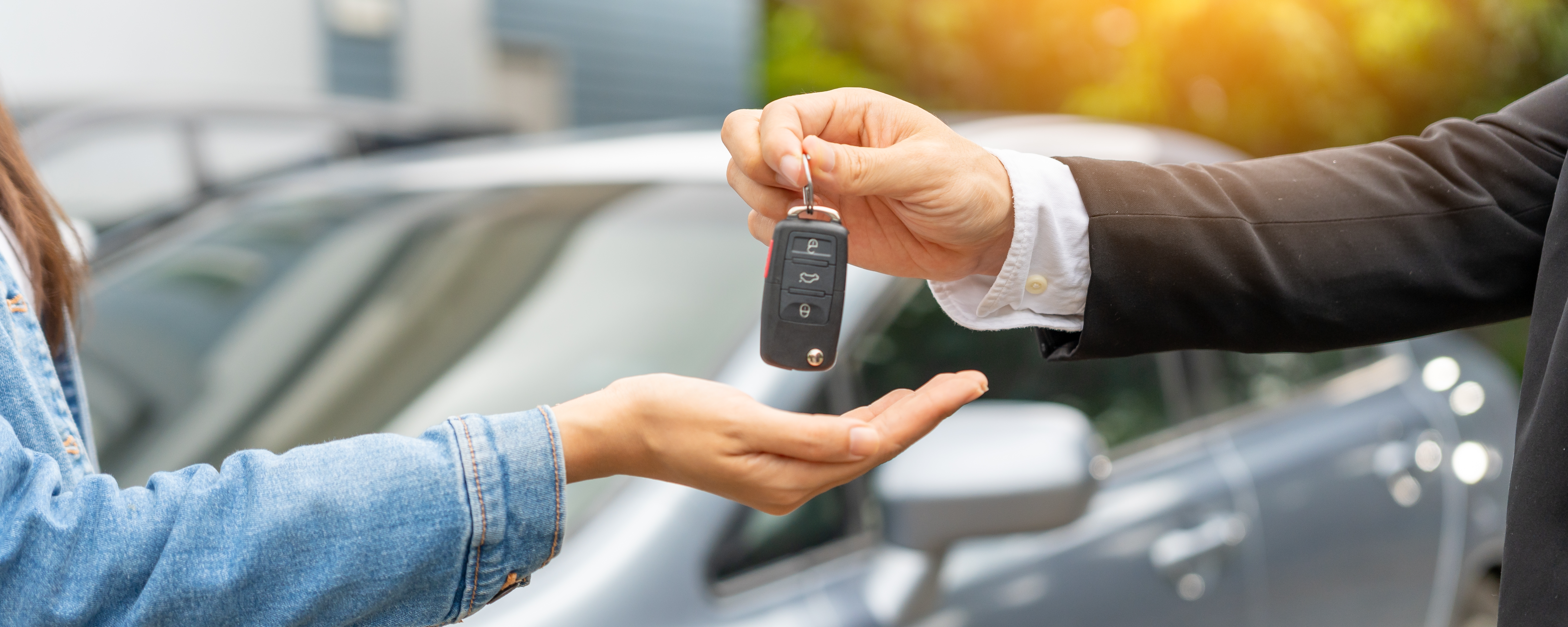 A car sales person handing car keys to new owner. 