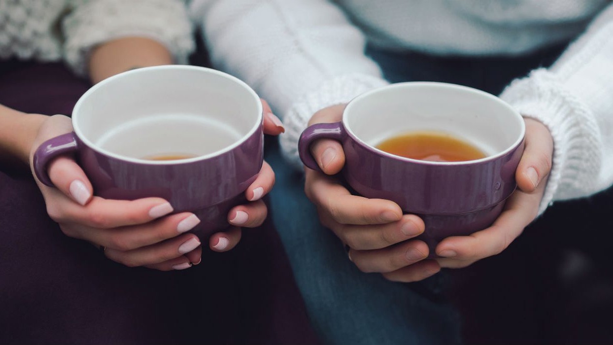 Two people holding cups of tea