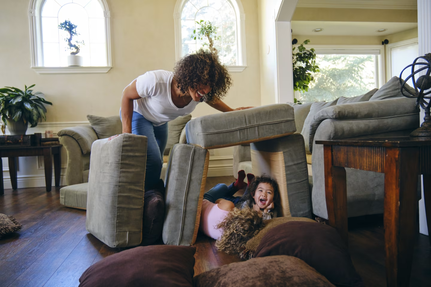 Woman and two children making cushion dens in living room