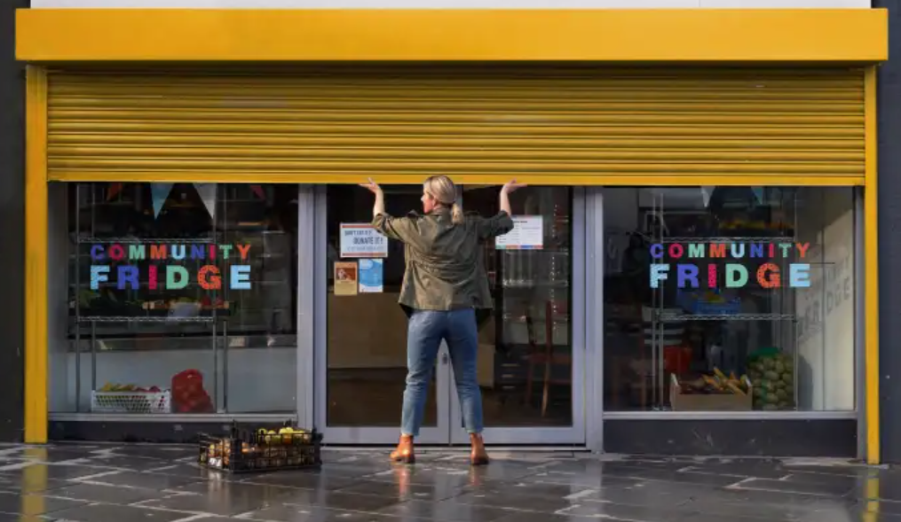 Woman opening up the doors to a community fridge project.