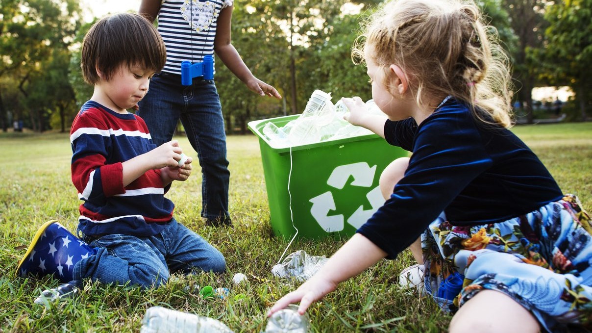 Children putting plastic bottles in a recycling box