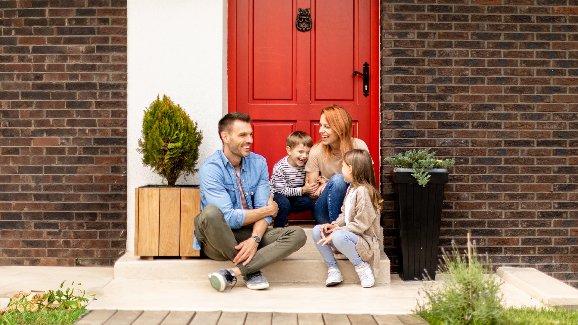 Family sitting in front of a red door