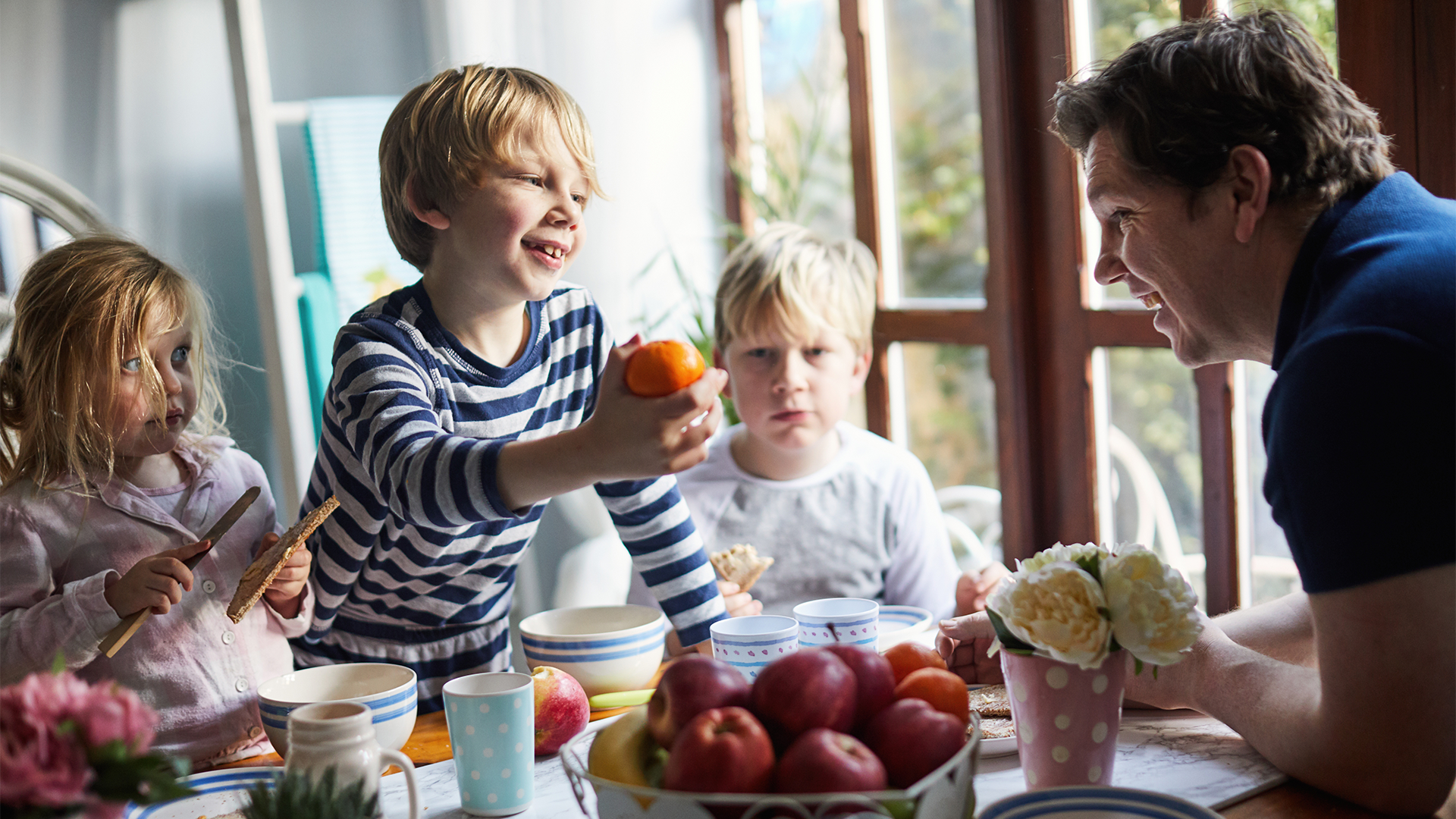 Children and father around a fruit bowl