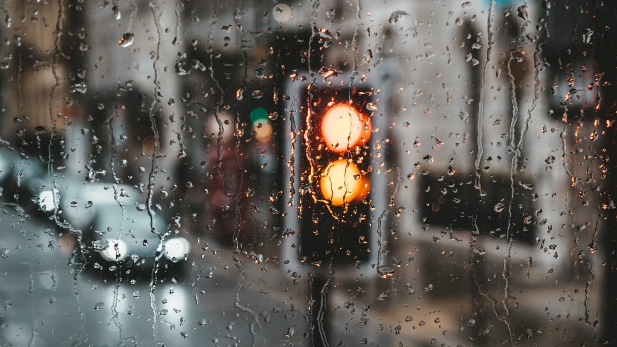 Rainy window with traffic lights and cars in the background