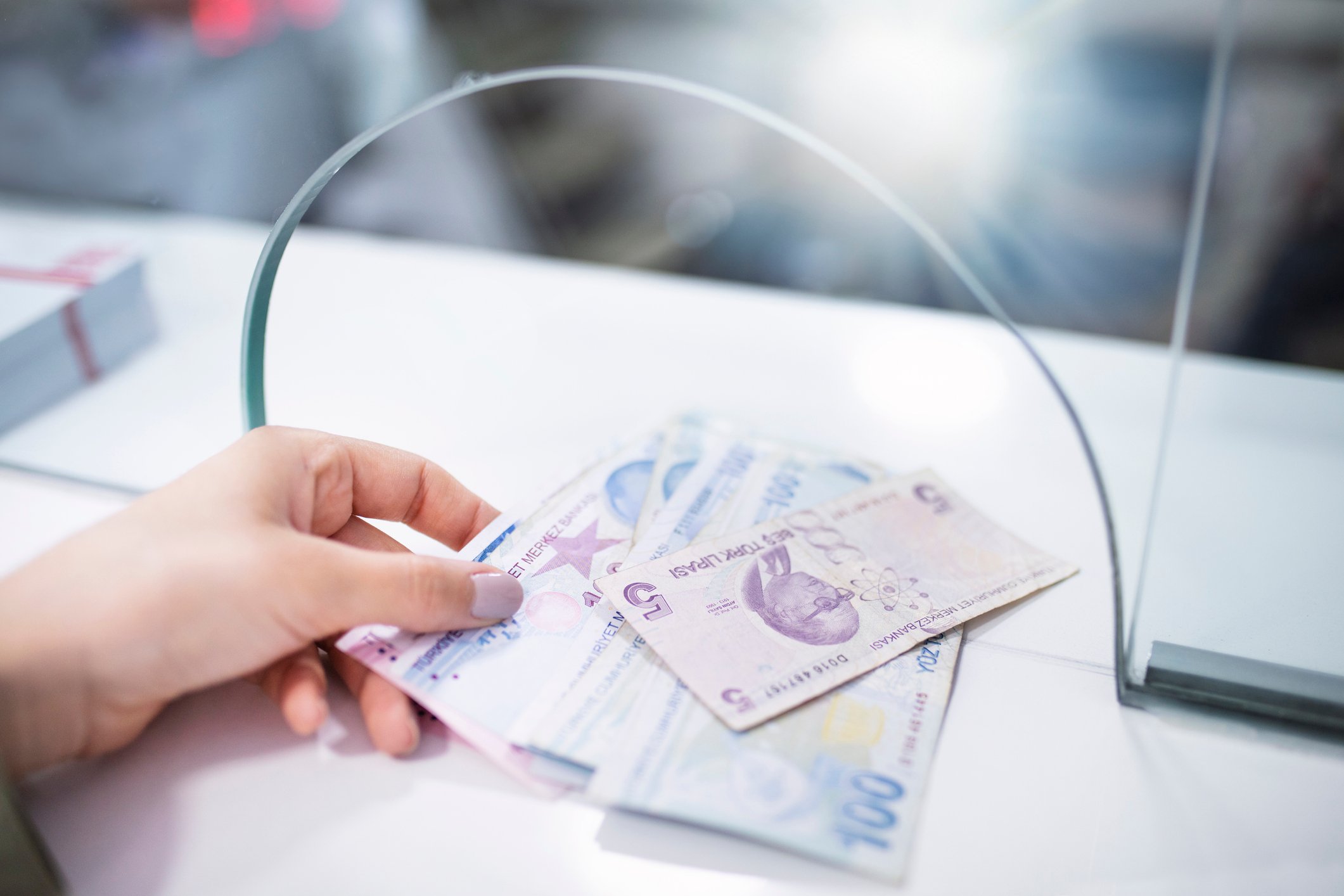 A hand holding several banknotes in different colours