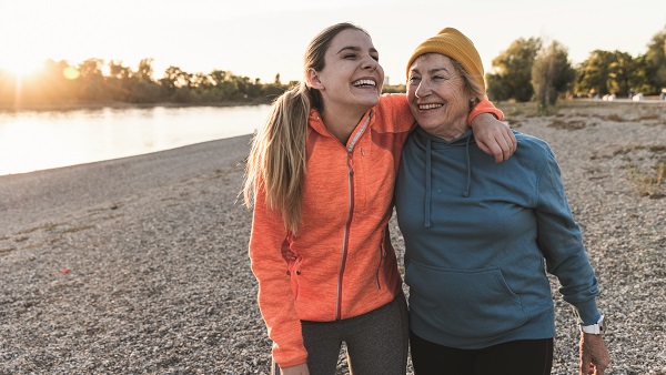 A mother and daughter enjoying a walk on a pebble beach.
