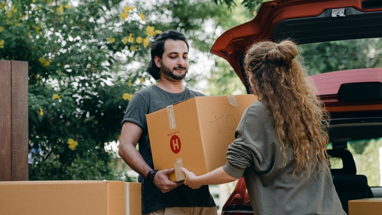 Two people carrying a cardboard box 