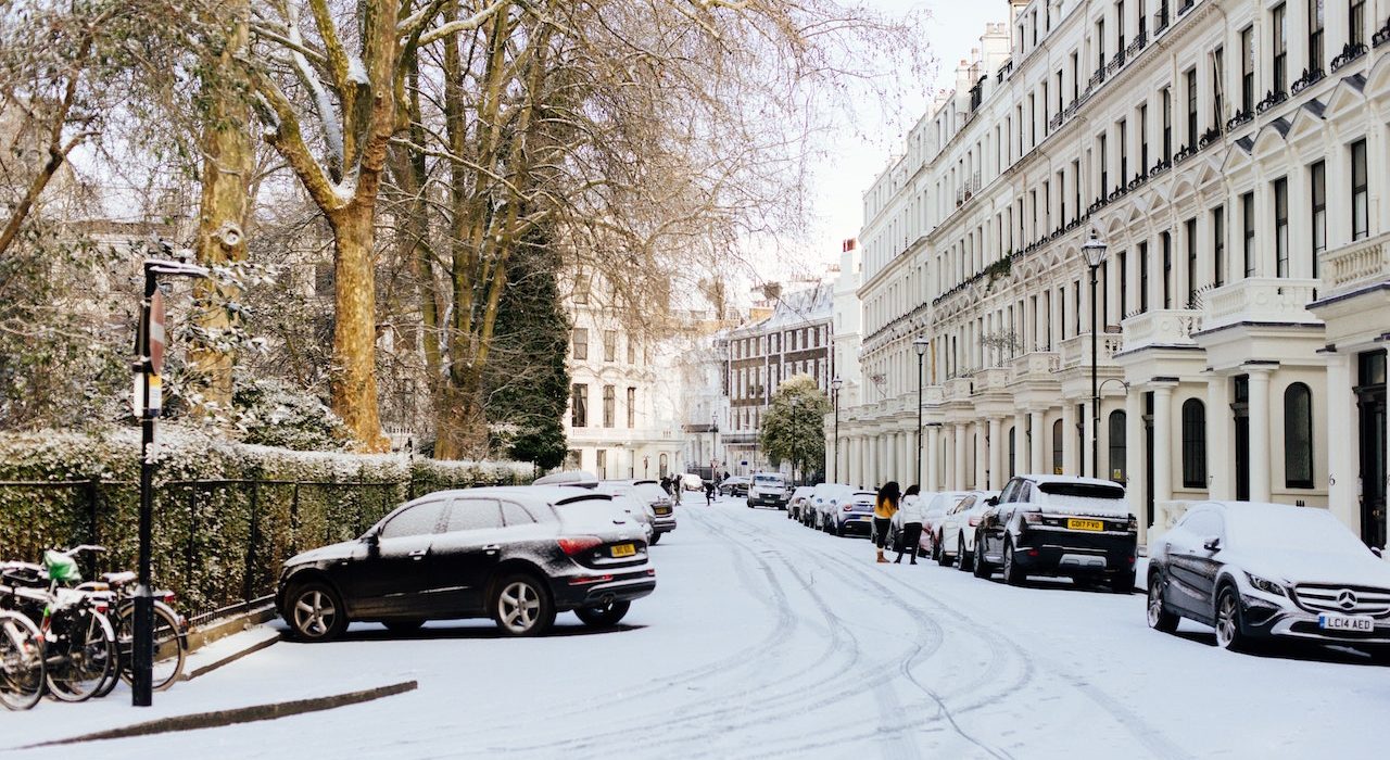 Snowy street in London with parked cars on either side