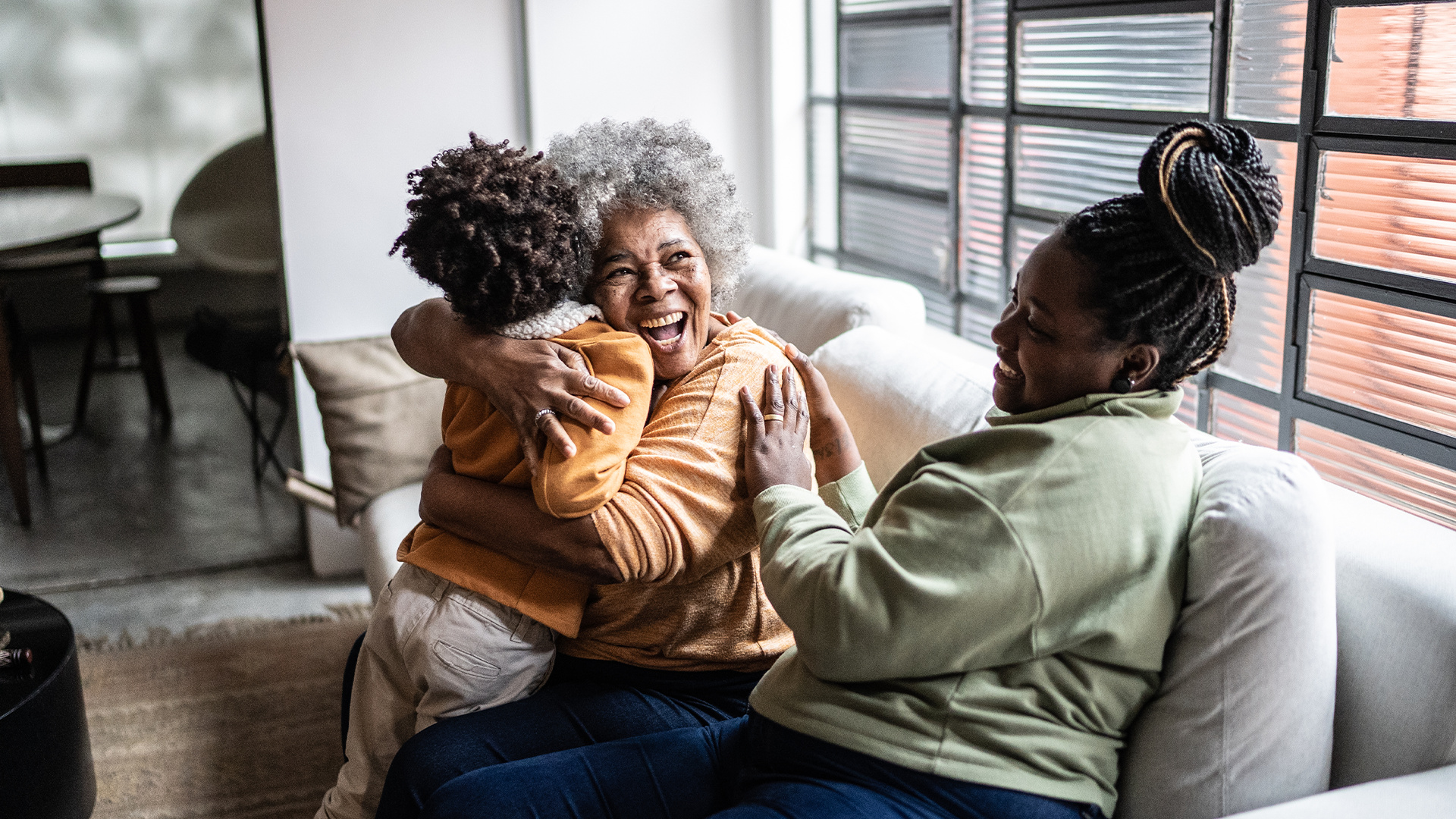 A grandmother sat with her family on the sofa.