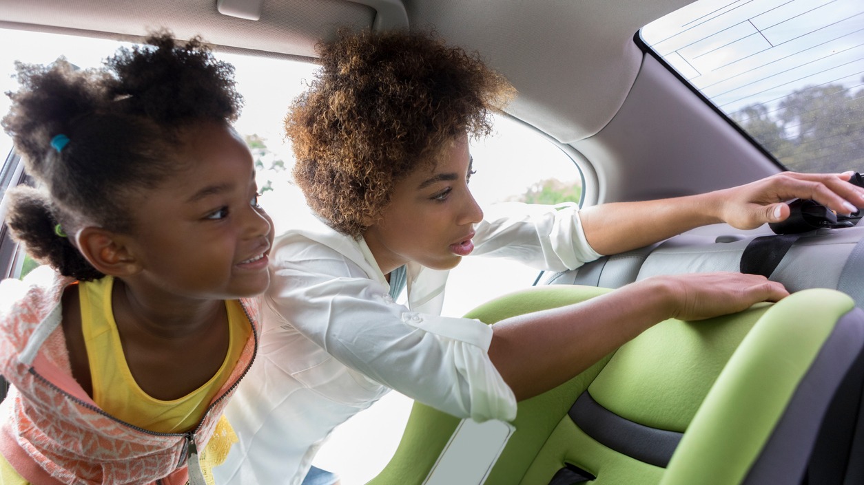 Person checking a car seat with a child