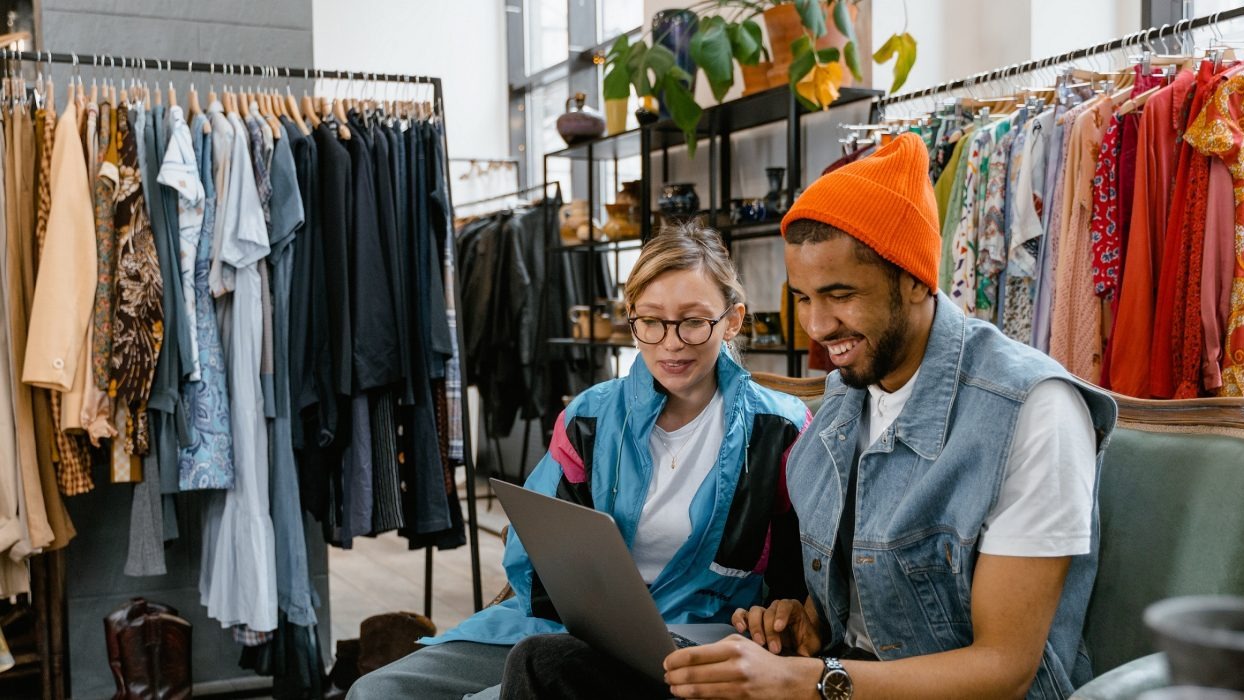 Two people sat looking at a laptop in a clothing store