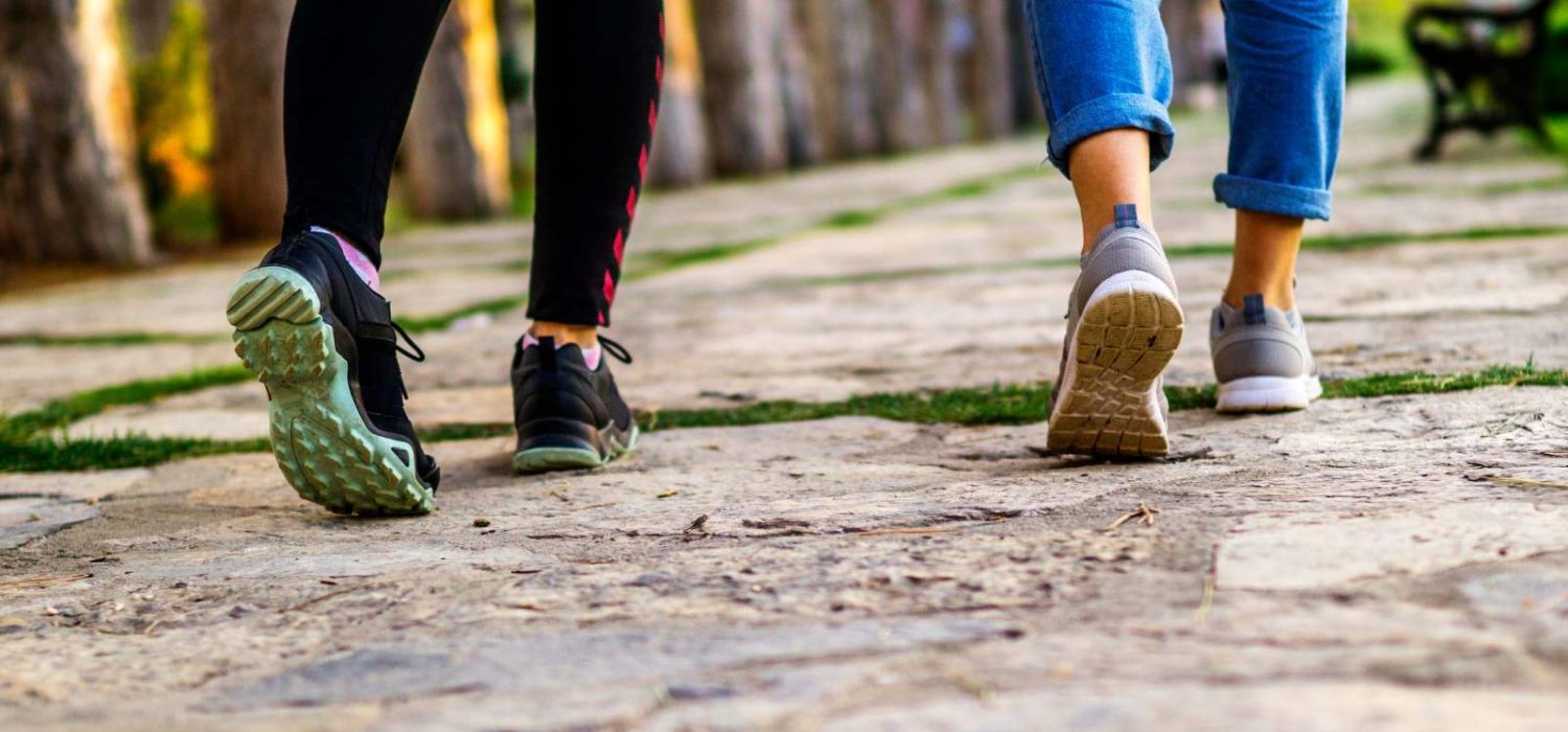 Two people walking on a path, focusing on their shoes.