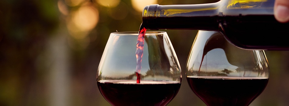 Rode wijn van PLUS wordt ingeschonken in een glas, met een tweede glas ernaast.