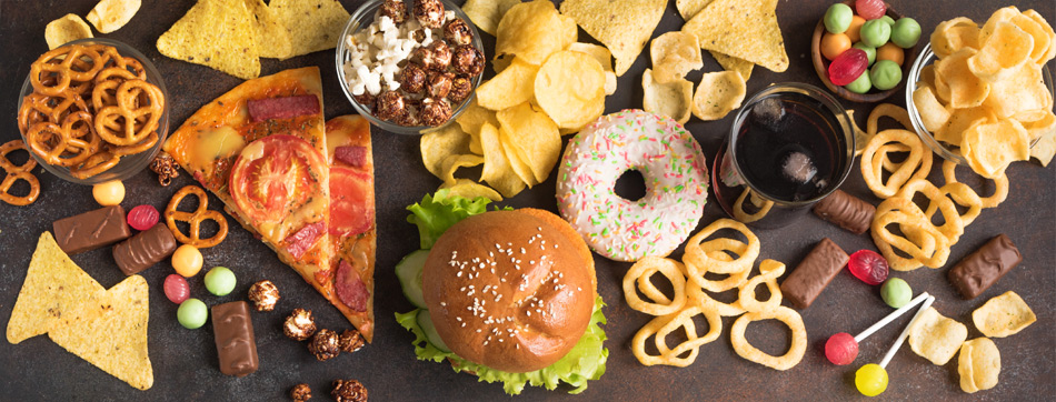 Snackselectie met onder andere pizza, hamburger, donut, chips, popcorn, snoep en frisdrank.