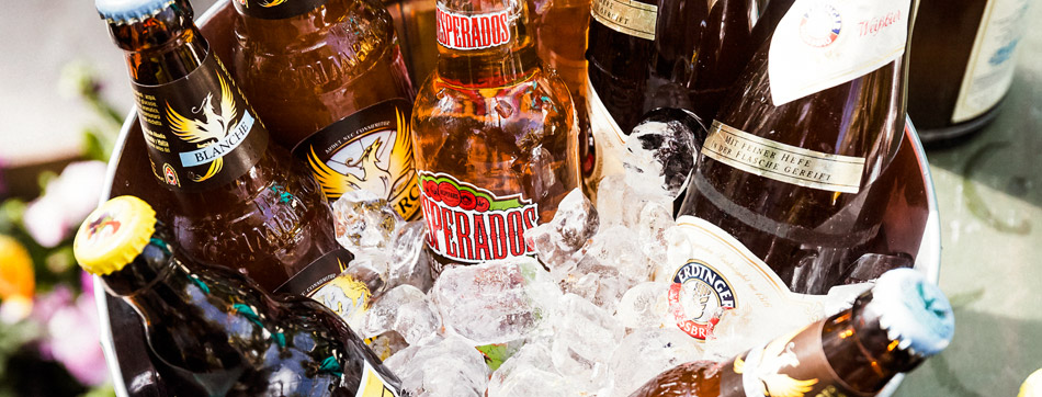 Selectie van bierflessen in een met ijs gevulde emmer. De flesjes zijn kleurrijk gelabeld met merken als Desperados en Erdinger.