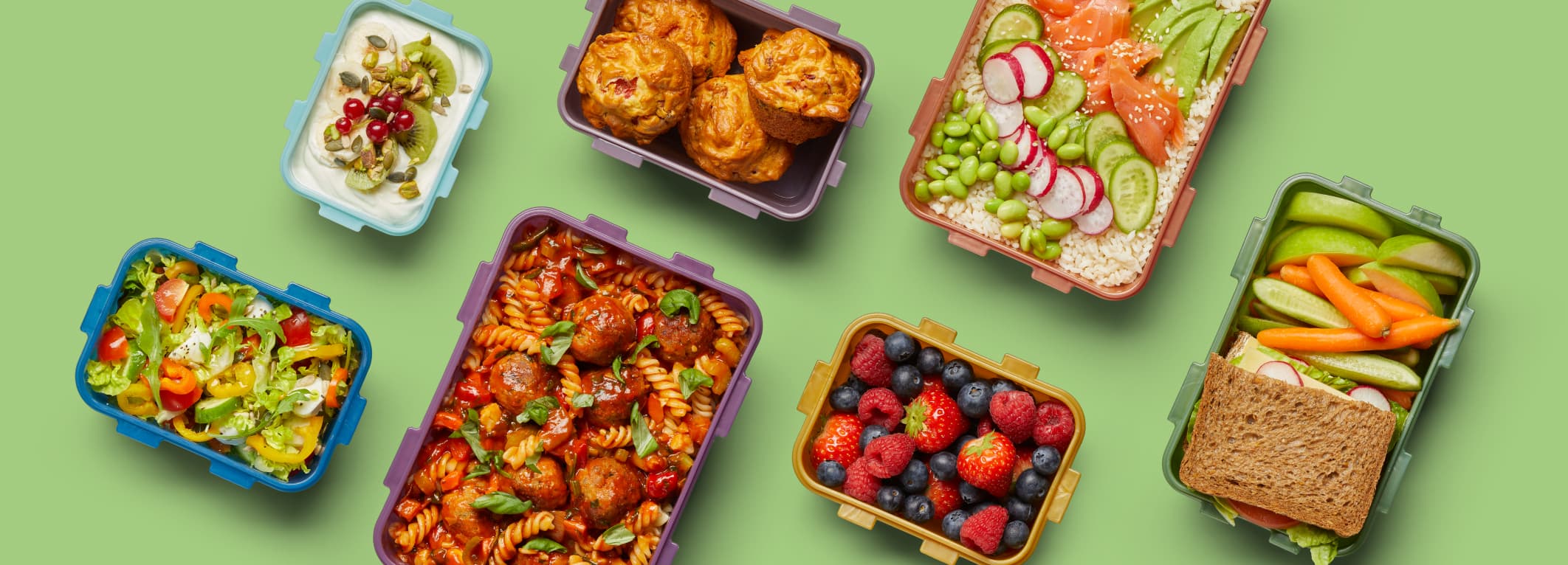 Verschillende LocknLock vershoudbakjes gevuld met diverse etenswaren, waaronder yoghurt, muffins, salades, pasta, gemengde bessen, en een sandwich.