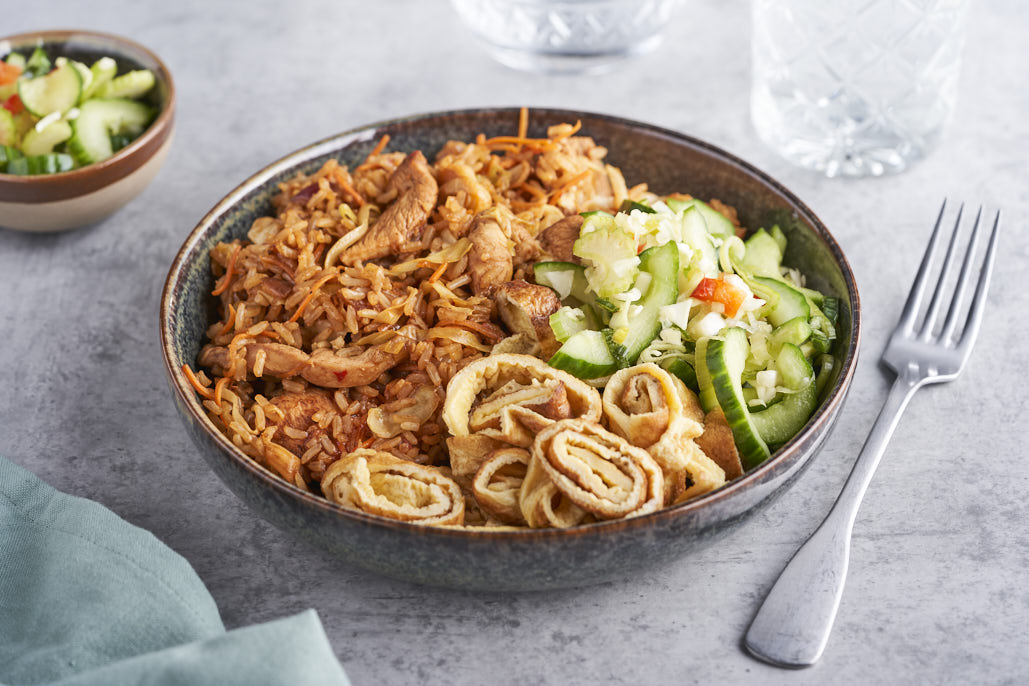 Gebakken rijst met kip ketjap, spitskool, wortel, omeletreepjes en atjar van komkommer