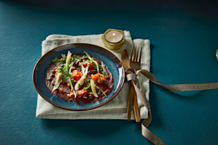 Carpaccio met pestosaus, rucola en zongedroogde tomaatjes