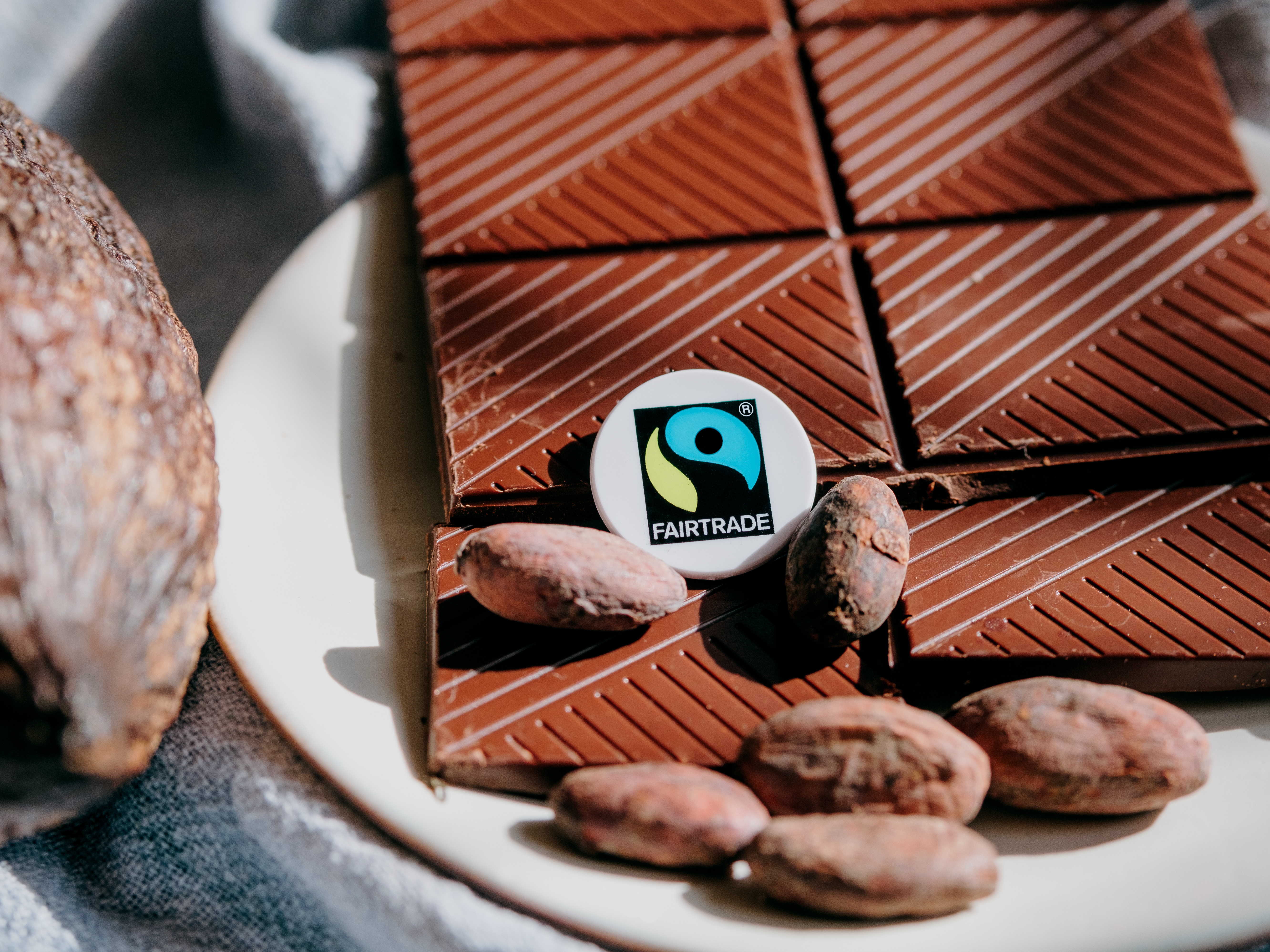 Chocolade met enkele cacaobonen en het Fairtrade-logo.