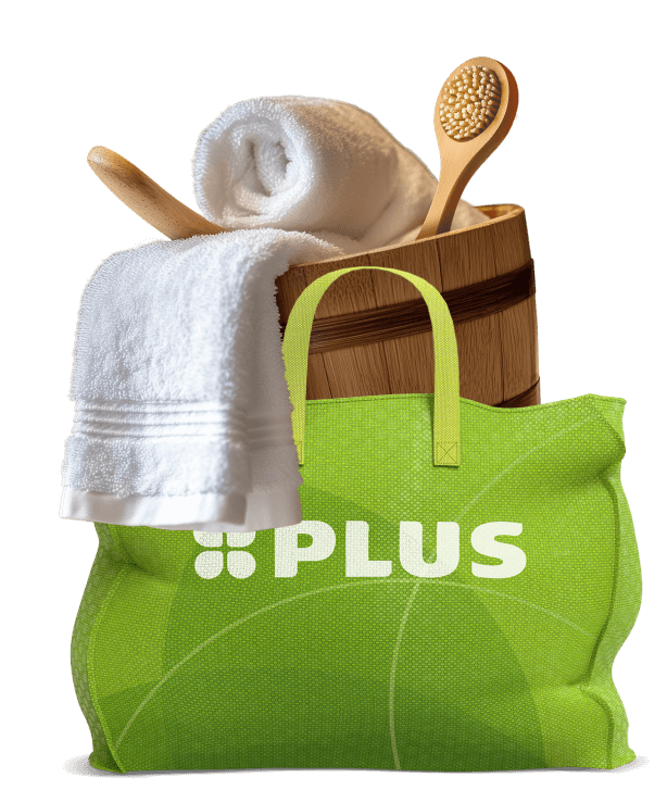 Groene PLUS-tas gevuld met wellnessproducten zoals een houten emmer, badborstel, witte handdoek en houten spatel.