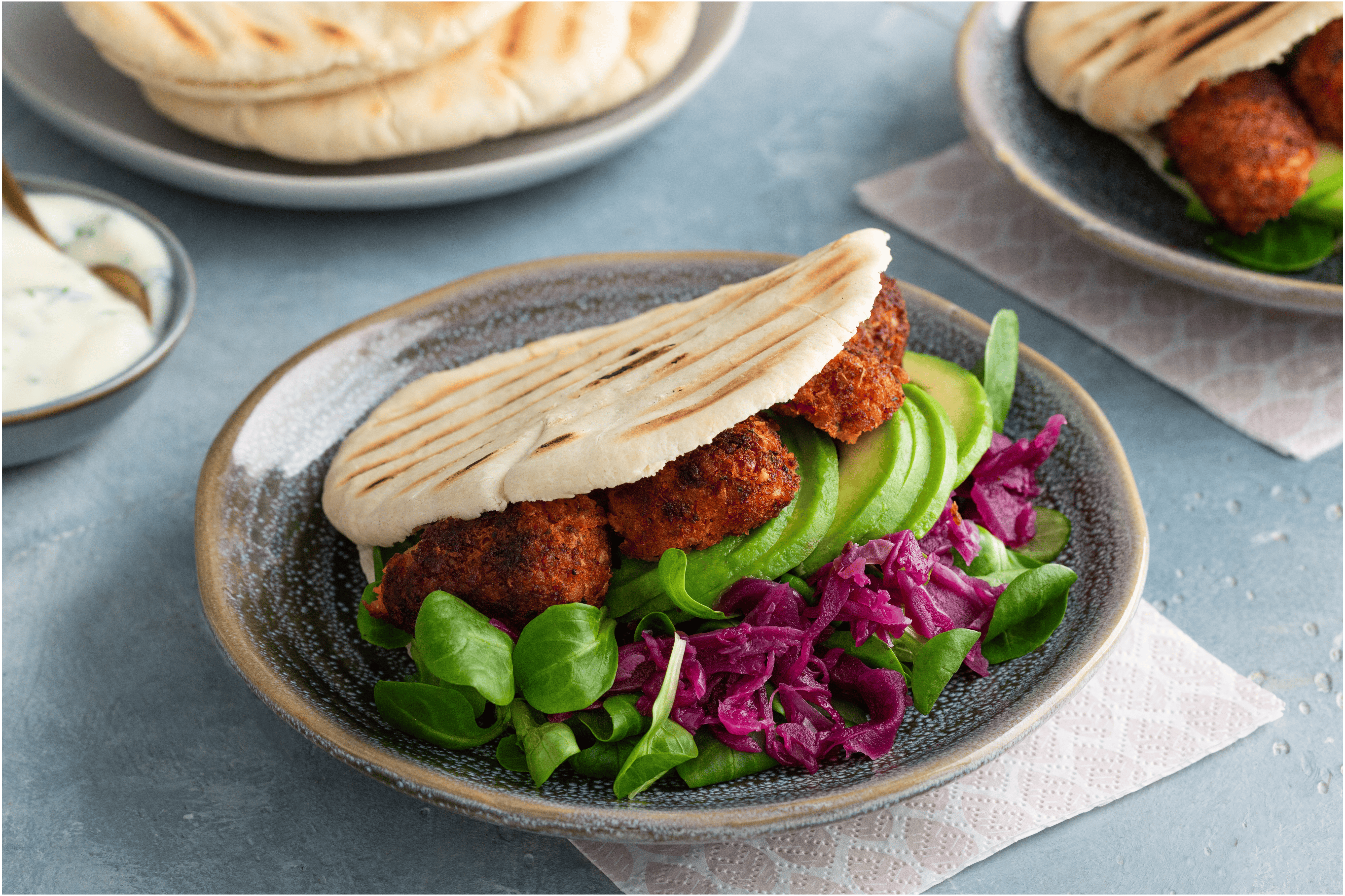 Vegan pita falafel met rode kool, avocado en soya yoghurtsaus