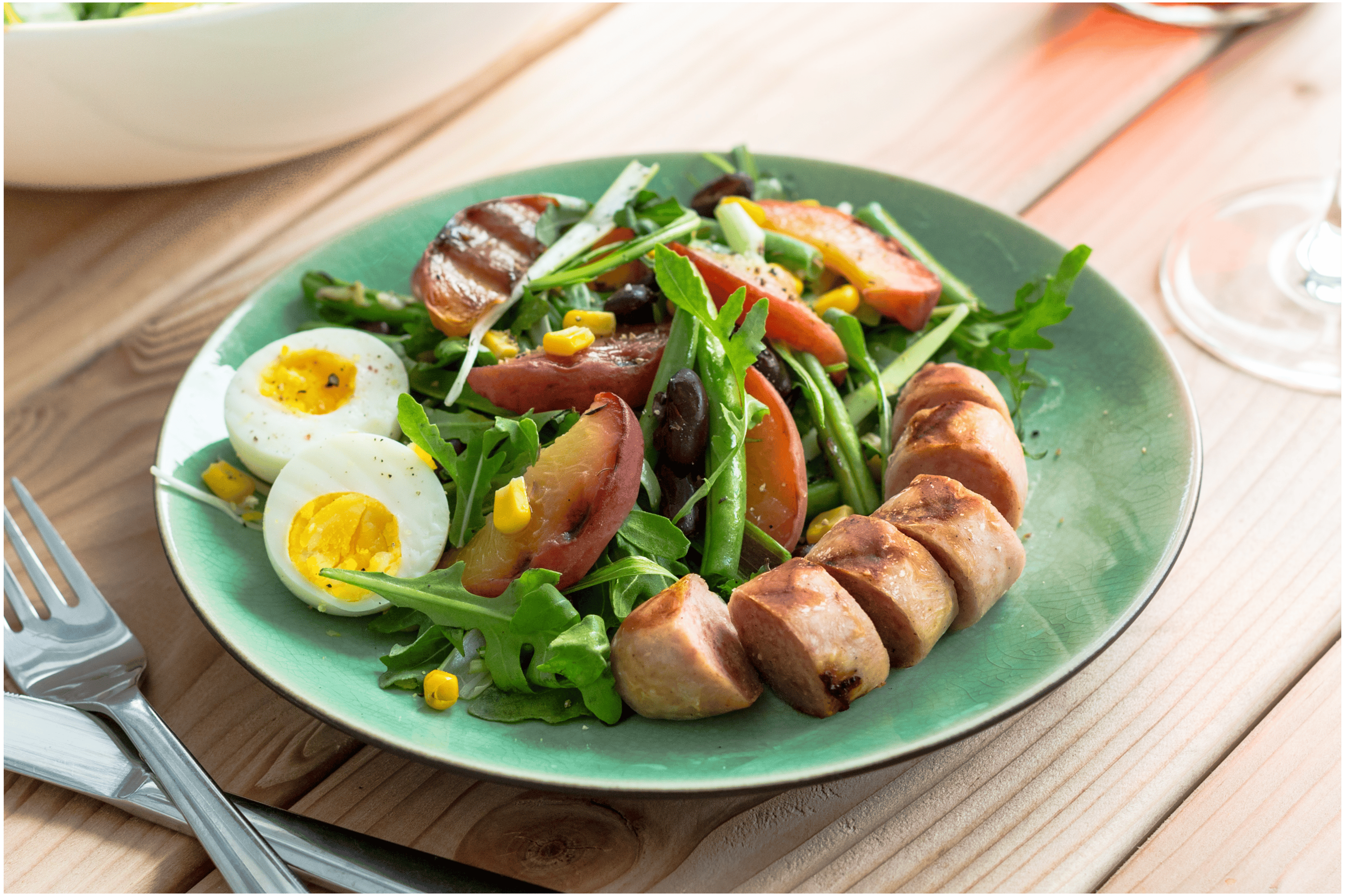 Zomerse maaltijdsalade met gebakken bonen en gegrilde worst