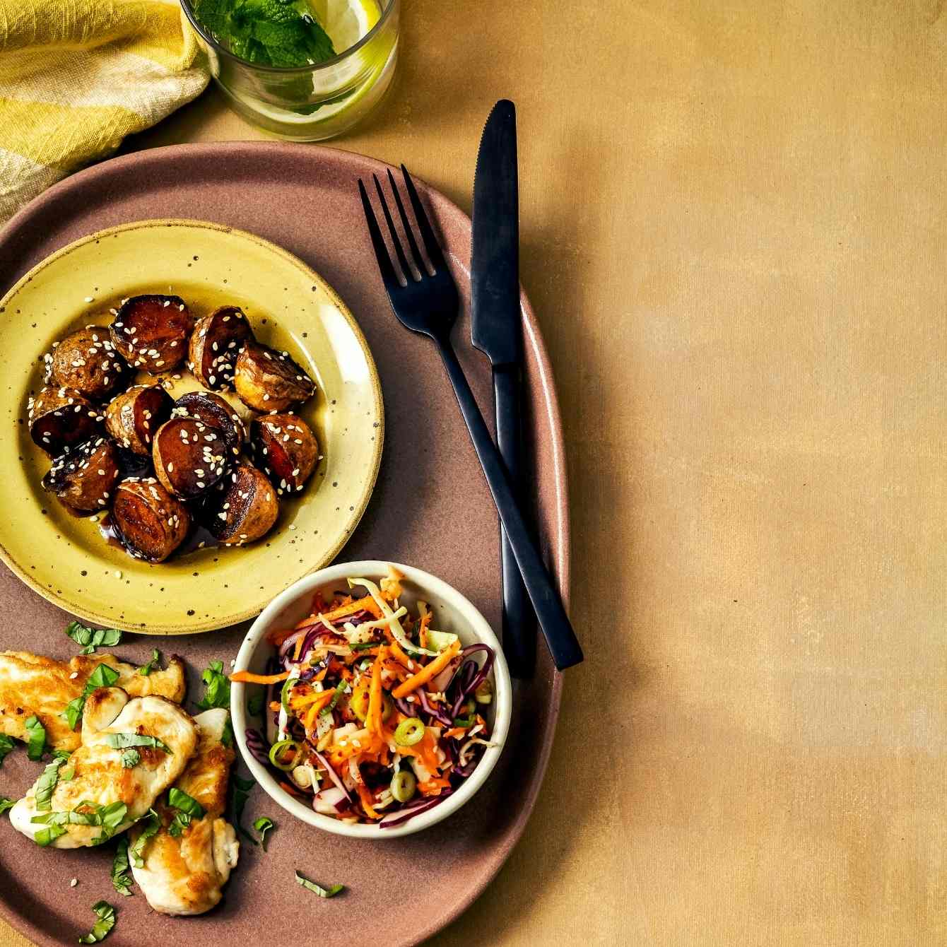 Geglaceerde sesamaardappeltjes met wortel-koolsalade en kip