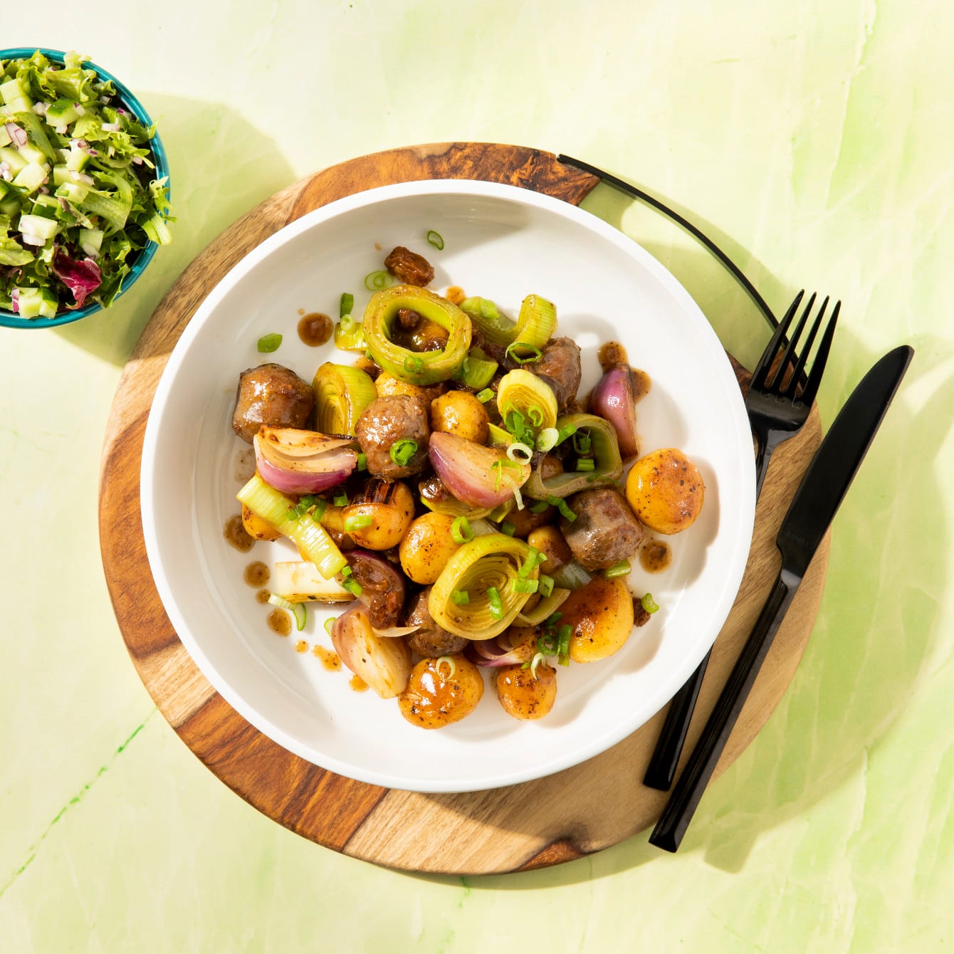 Eenpansschotel van krieltjes, prei, rode ui en rundersaucijs met rozijntjes