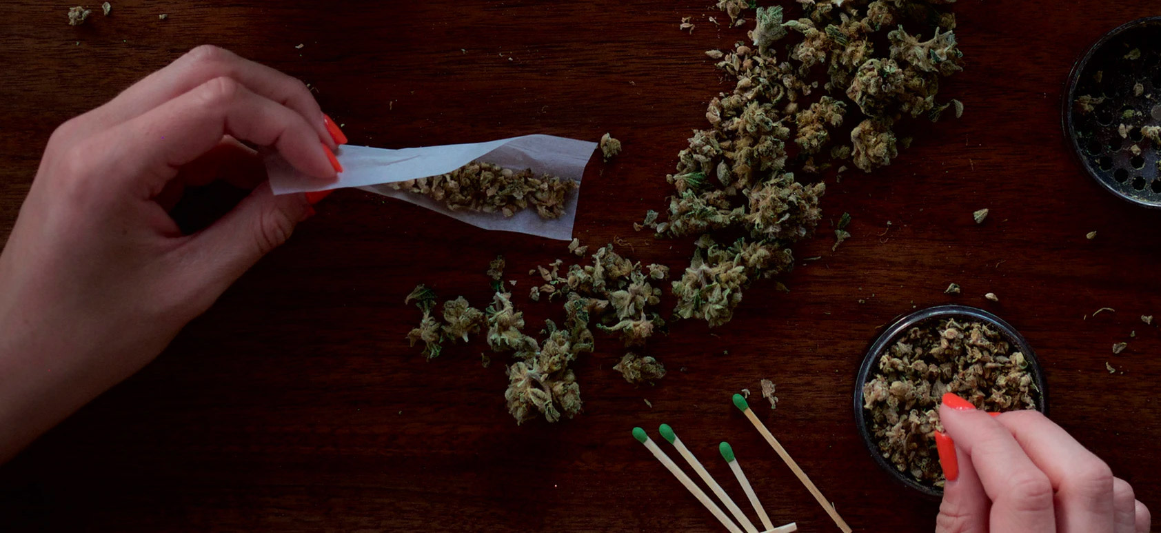 woman rolling a joint with pink nails