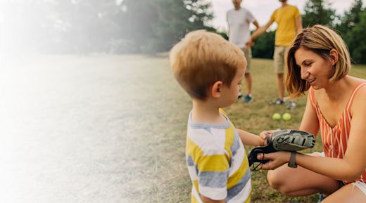 A mom helps her son with his baseball glove