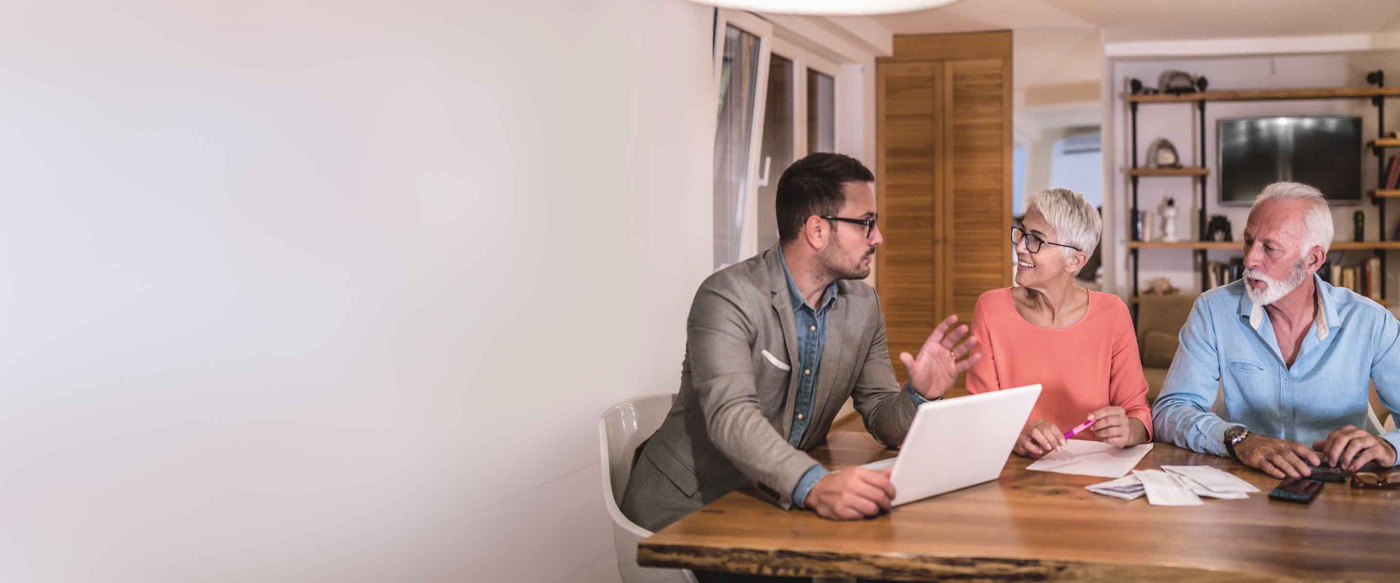 A young, white, male financial producer counsels a senior white couple about life insurance options.