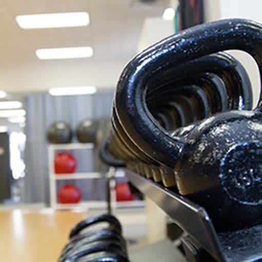 A close up picture of kettle bells on a rack in a small gym