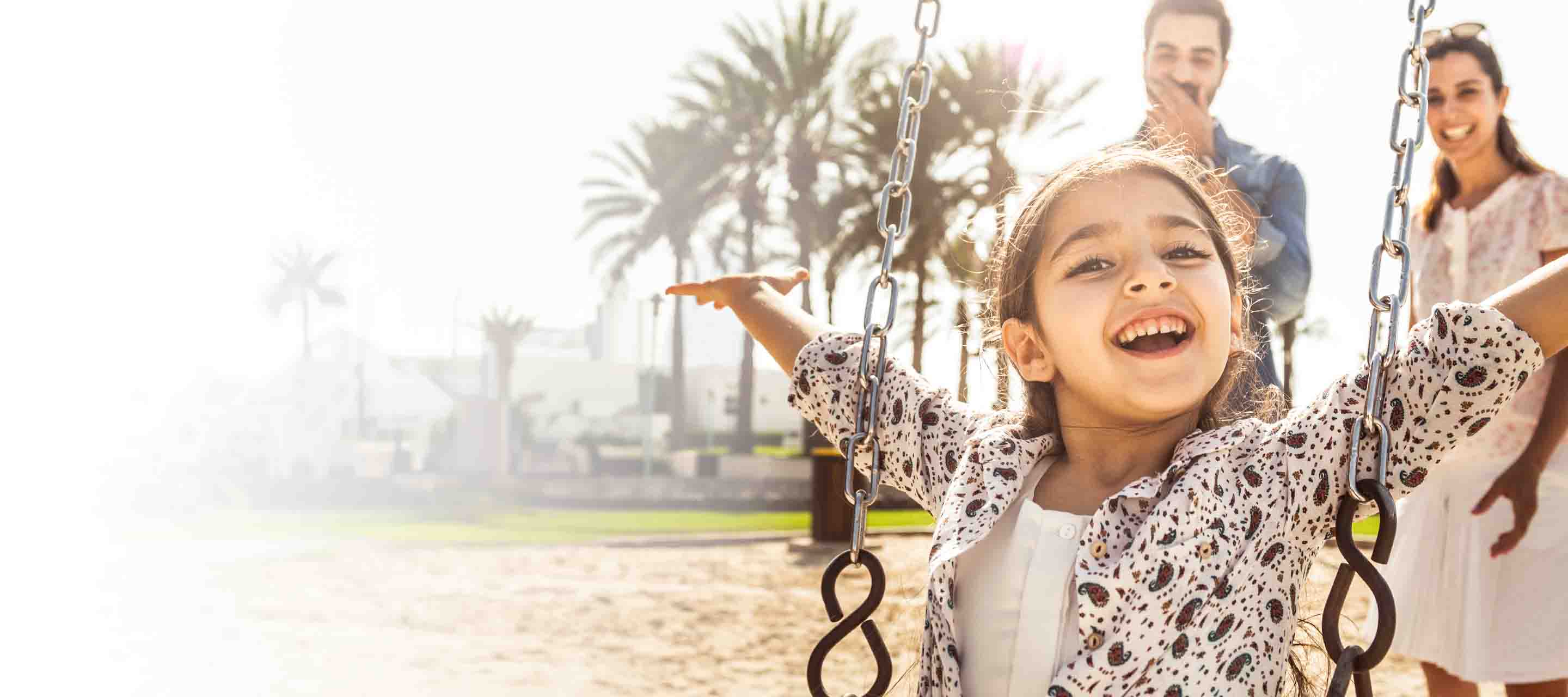 Young girl on a swing being pushed by her parents