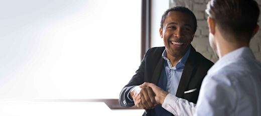 A Black businessman shakes hands with a white male colleague