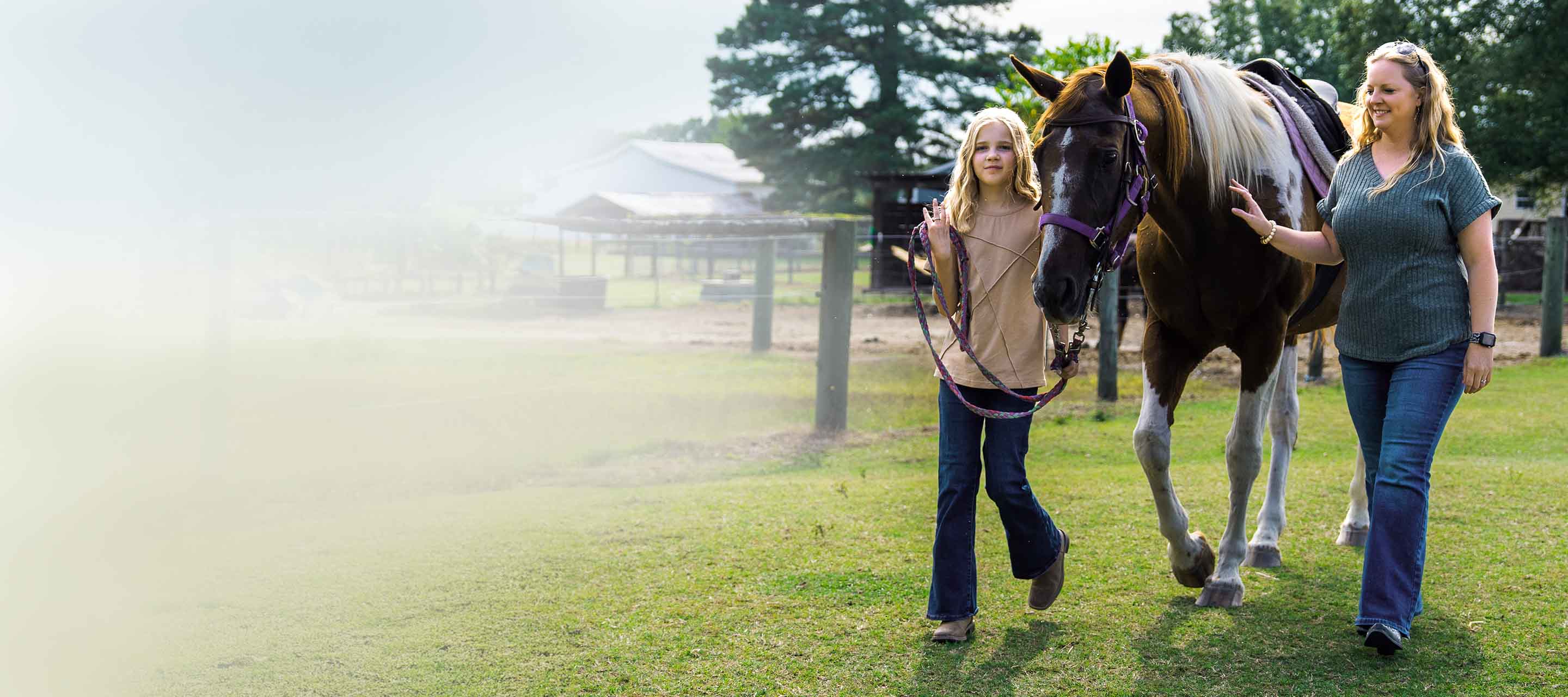 Mother and daughter walking with a horse.