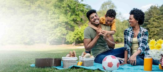 A young Black family enjoys a picnic in the park on a sunny day