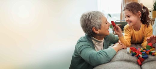 Grandmother and granddaughter enjoy playful moments together, building with wooden toy blocks in their home
